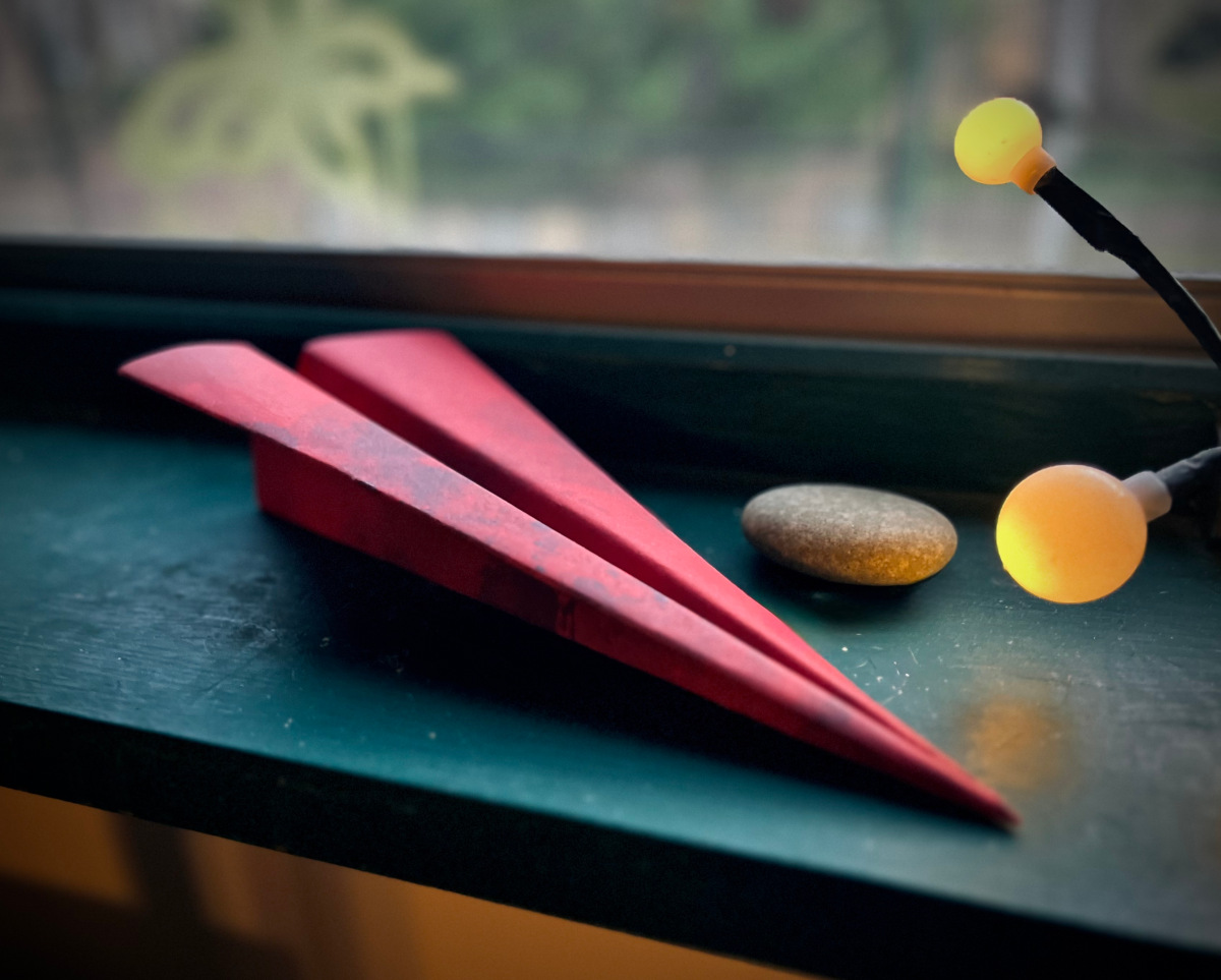 A red letter paper airplane by the window.